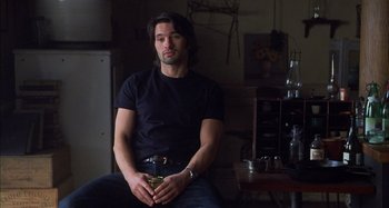 Movie still from “Unfaithful” (2002), directed by Adrian Lyne – A man sitting on a chair in a dark room; Medium shot, Low angle