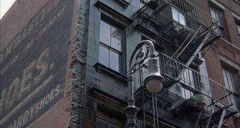 Movie still from “Unfaithful” (2002), directed by Adrian Lyne – A street light in front of an apartment building with fire escapes; Extreme Wide shot, Overhead angle