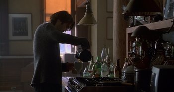 Movie still from “Unfaithful” (2002), directed by Adrian Lyne – A person pouring a cup of tea on a stove top; Medium shot, Low angle