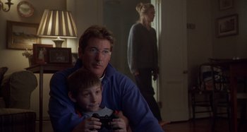 Movie still from “Unfaithful” (2002), directed by Adrian Lyne – A man and a boy are playing a video game; Medium shot, Over the shoulder angle