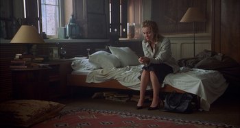 Movie still from “Unfaithful” (2002), directed by Adrian Lyne – A woman sitting on top of a bed looking at her cell phone; Wide shot, High angle