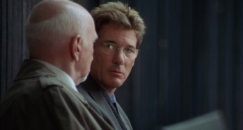 Movie still from “Unfaithful” (2002), directed by Adrian Lyne – A man in a business suit and a man in a business suit and glasses; Close Up shot, Over the shoulder angle
