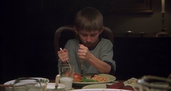 Movie still from “Unfaithful” (2002), directed by Adrian Lyne – A young boy sitting at a dinner table eating a meal; Medium shot, High angle