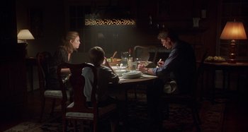 Movie still from “Unfaithful” (2002), directed by Adrian Lyne – Three people sitting at a table in a dark room; Wide shot, Over the shoulder angle