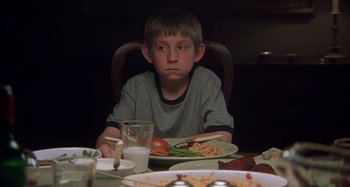 Movie still from “Unfaithful” (2002), directed by Adrian Lyne – A boy sitting at a table with a plate of food in front of him; Close Up shot, Over the shoulder angle