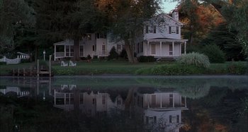 Movie still from “Unfaithful” (2002), directed by Adrian Lyne – A white house sitting next to a body of water; Extreme Wide shot, High angle