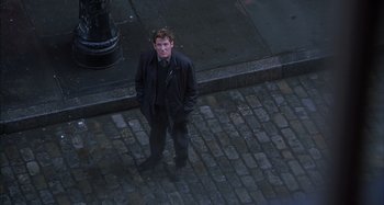 Movie still from “Unfaithful” (2002), directed by Adrian Lyne – A man standing on the side of the street; Wide shot, High angle