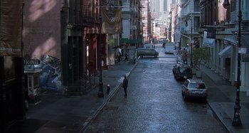 Movie still from “Unfaithful” (2002), directed by Adrian Lyne – A person walking down a street near a building; Extreme Wide shot, High angle