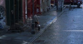 Movie still from “Unfaithful” (2002), directed by Adrian Lyne – A man walking down the sidewalk of a city street; Extreme Wide shot, Overhead angle