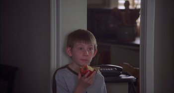 Movie still from “Unfaithful” (2002), directed by Adrian Lyne – A young boy eating a piece of food; Close Up shot, High angle