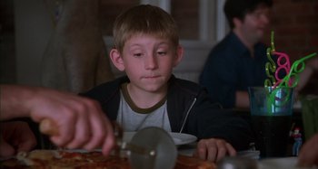 Movie still from “Unfaithful” (2002), directed by Adrian Lyne – A young boy sitting in front of a pizza cutter; Close Up shot, Over the shoulder angle