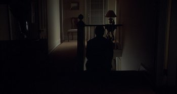 Movie still from “Unfaithful” (2002), directed by Adrian Lyne – A man sitting in a chair in a dark room; Wide shot, High angle
