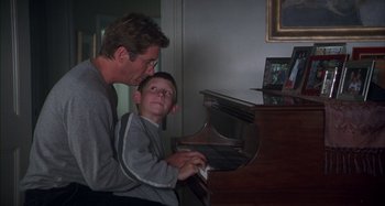 Movie still from “Unfaithful” (2002), directed by Adrian Lyne – A man and a boy playing a piano together; Medium shot, Over the shoulder angle