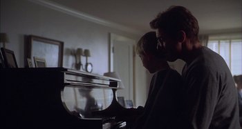 Movie still from “Unfaithful” (2002), directed by Adrian Lyne – A man and a child playing a piano; Medium shot, Over the shoulder angle