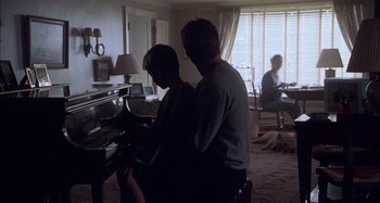 Movie still from “Unfaithful” (2002), directed by Adrian Lyne – A man and a woman sitting in front of a piano in a living room; Wide shot, Over the shoulder angle