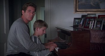 Movie still from “Unfaithful” (2002), directed by Adrian Lyne – A man and a boy playing a piano together; Medium shot, Low angle