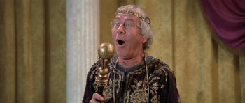 Movie still from “History of the World: Part I” (1981), directed by Mel Brooks – An older man holding a golden trophy in a room with columns; Close Up shot, Low angle
