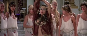 Movie still from “History of the World: Part I” (1981), directed by Mel Brooks – A woman in a belly dancing outfit with other women in the background; Medium shot, Over the shoulder angle