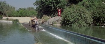 Movie still from “History of the World: Part I” (1981), directed by Mel Brooks – A man standing on top of a waterfall next to a body of water; Extreme Wide shot, High angle