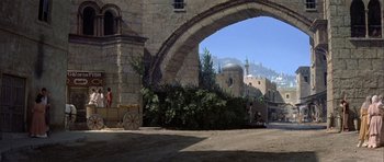 Movie still from “History of the World: Part I” (1981), directed by Mel Brooks – An arch in the middle of a street with trees and buildings in the background; Extreme Wide shot, High angle