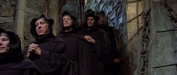 Movie still from “History of the World: Part I” (1981), directed by Mel Brooks – A group of people dressed in black robes and hoods; Medium shot, High angle
