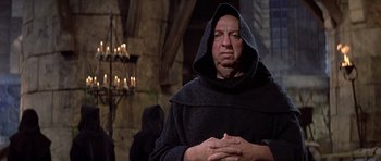 Movie still from “History of the World: Part I” (1981), directed by Mel Brooks – A man wearing a black robe and a black hood; Medium shot, Low angle