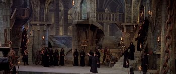 Movie still from “History of the World: Part I” (1981), directed by Mel Brooks – A group of people dressed in black standing in front of a building; Extreme Wide shot, High angle