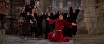 Movie still from “History of the World: Part I” (1981), directed by Mel Brooks – A group of people dressed in black and wearing red robes; Wide shot, High angle