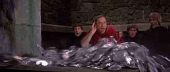 Movie still from “History of the World: Part I” (1981), directed by Mel Brooks – Two men are sitting in front of a pile of coins; Medium shot, Low angle