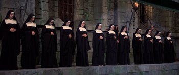 Movie still from “History of the World: Part I” (1981), directed by Mel Brooks – A group of women dressed in black standing on a stage; Wide shot, High angle