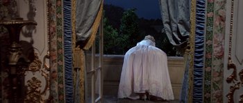 Movie still from “History of the World: Part I” (1981), directed by Mel Brooks – A woman dressed in a white dress looking out of a window; Wide shot, High angle