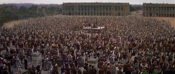 Movie still from “History of the World: Part I” (1981), directed by Mel Brooks – A crowd of people standing in front of a large building; Extreme Wide shot, High angle