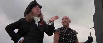Movie still from “History of the World: Part I” (1981), directed by Mel Brooks – Two men dressed in medieval clothing one of them is wearing a hat; Medium shot, Low angle
