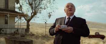 Movie still from “Hitchcock” (2012), directed by Sacha Gervasi – A man in a suit and tie holding a cup in his hand; Medium shot, Low angle