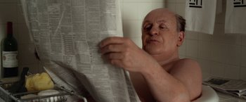 Movie still from “Hitchcock” (2012), directed by Sacha Gervasi – An older man reading a newspaper in a bathroom; Close Up shot, Over the shoulder angle