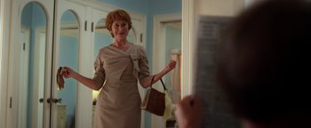 Movie still from “Hitchcock” (2012), directed by Sacha Gervasi – An older woman in a tan dress in front of a mirror; Medium shot, Over the shoulder angle