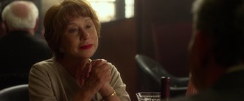 Movie still from “Hitchcock” (2012), directed by Sacha Gervasi – An older woman sitting at a table in front of a wine glass; Close Up shot, Over the shoulder angle
