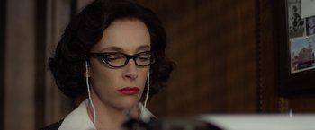 Movie still from “Hitchcock” (2012), directed by Sacha Gervasi – A woman wearing glasses and a white shirt is listening to music; Close Up shot, Low angle
