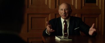 Movie still from “Hitchcock” (2012), directed by Sacha Gervasi – An older man sitting at a table in front of an open book; Close Up shot, High angle