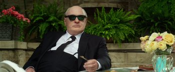 Movie still from “Hitchcock” (2012), directed by Sacha Gervasi – An older man in a suit and tie eating a piece of food; Medium shot, Low angle