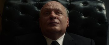 Movie still from “Hitchcock” (2012), directed by Sacha Gervasi – An older man wearing a suit and tie looking upward; Close Up shot, Low angle