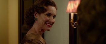 Movie still from “Hitchcock” (2012), directed by Sacha Gervasi – A woman smiling at the camera in front of a lamp; Close Up shot, Over the shoulder angle