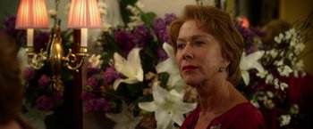 Movie still from “Hitchcock” (2012), directed by Sacha Gervasi – An older woman standing in front of a flower arrangement; Close Up shot, Over the shoulder angle