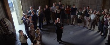 Movie still from “Hitchcock” (2012), directed by Sacha Gervasi – A group of people standing in a room with a man holding a cane; Wide shot, Overhead angle