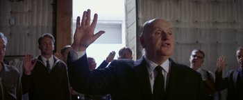 Movie still from “Hitchcock” (2012), directed by Sacha Gervasi – A man in a suit and tie raising his hand; Close Up shot, Low angle
