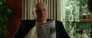 Movie still from “Hitchcock” (2012), directed by Sacha Gervasi – An older man reading a newspaper in a room; Close Up shot, Low angle