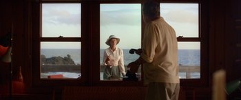 Movie still from “Hitchcock” (2012), directed by Sacha Gervasi – An older man and a woman standing in front of a window looking out at the ocean; Medium shot, Over the shoulder angle