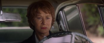 Movie still from “Hitchcock” (2012), directed by Sacha Gervasi – An older woman sitting in a car looking at the camera; Close Up shot, Low angle