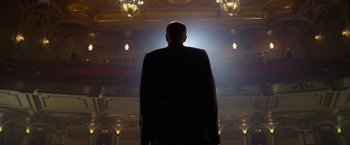 Movie still from “Hitchcock” (2012), directed by Sacha Gervasi – A man standing in front of a stage lit up by lights; Wide shot, Low angle