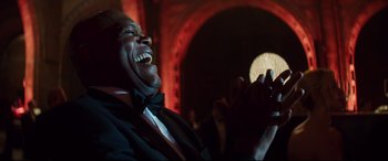 Movie still from “Hitman's Wife's Bodyguard” (2021), directed by Patrick Hughes – A man in a suit and bow tie holding a cell phone; Close Up shot, Low angle